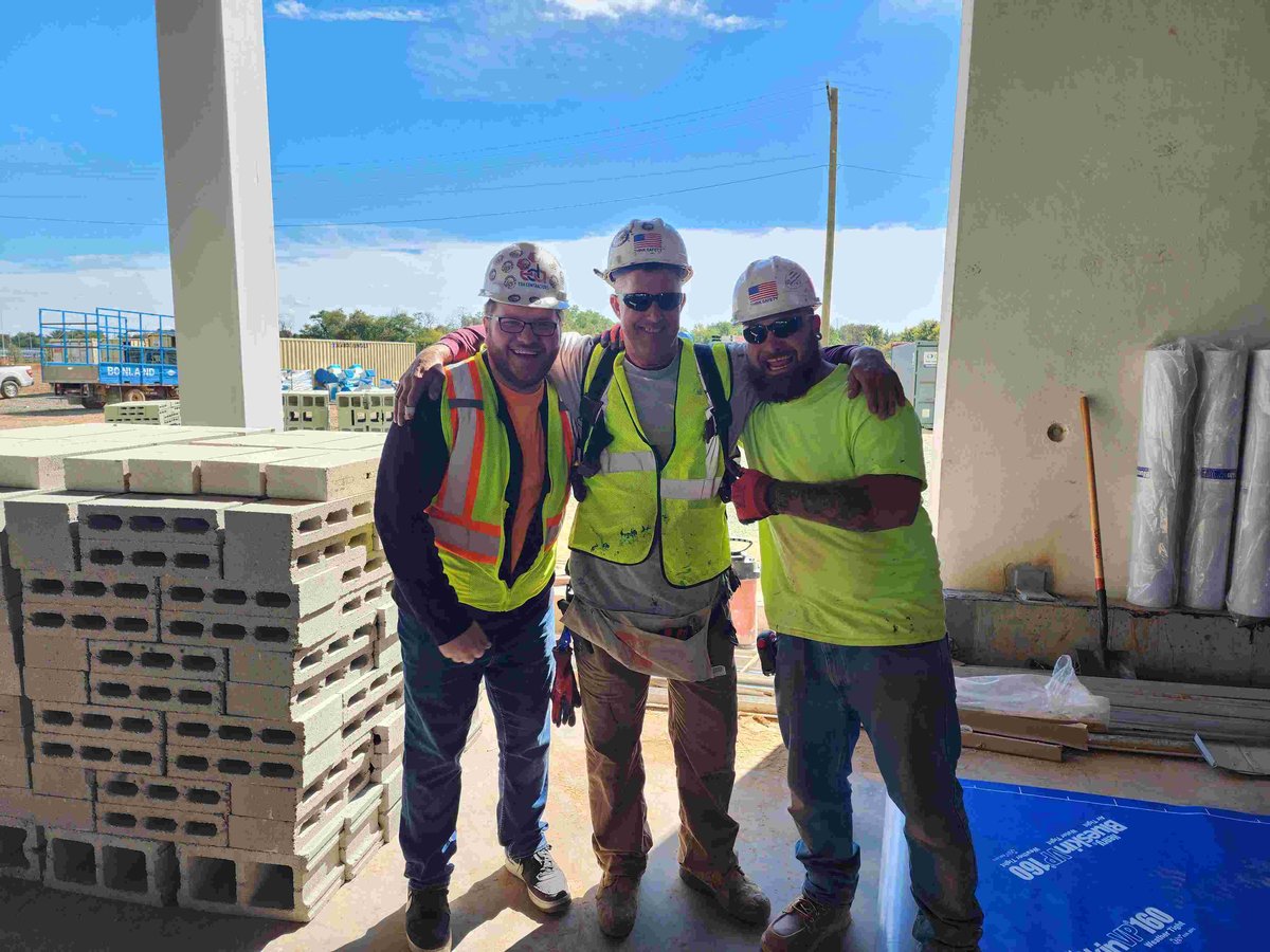 Three construction workers on jobsite looking at camera