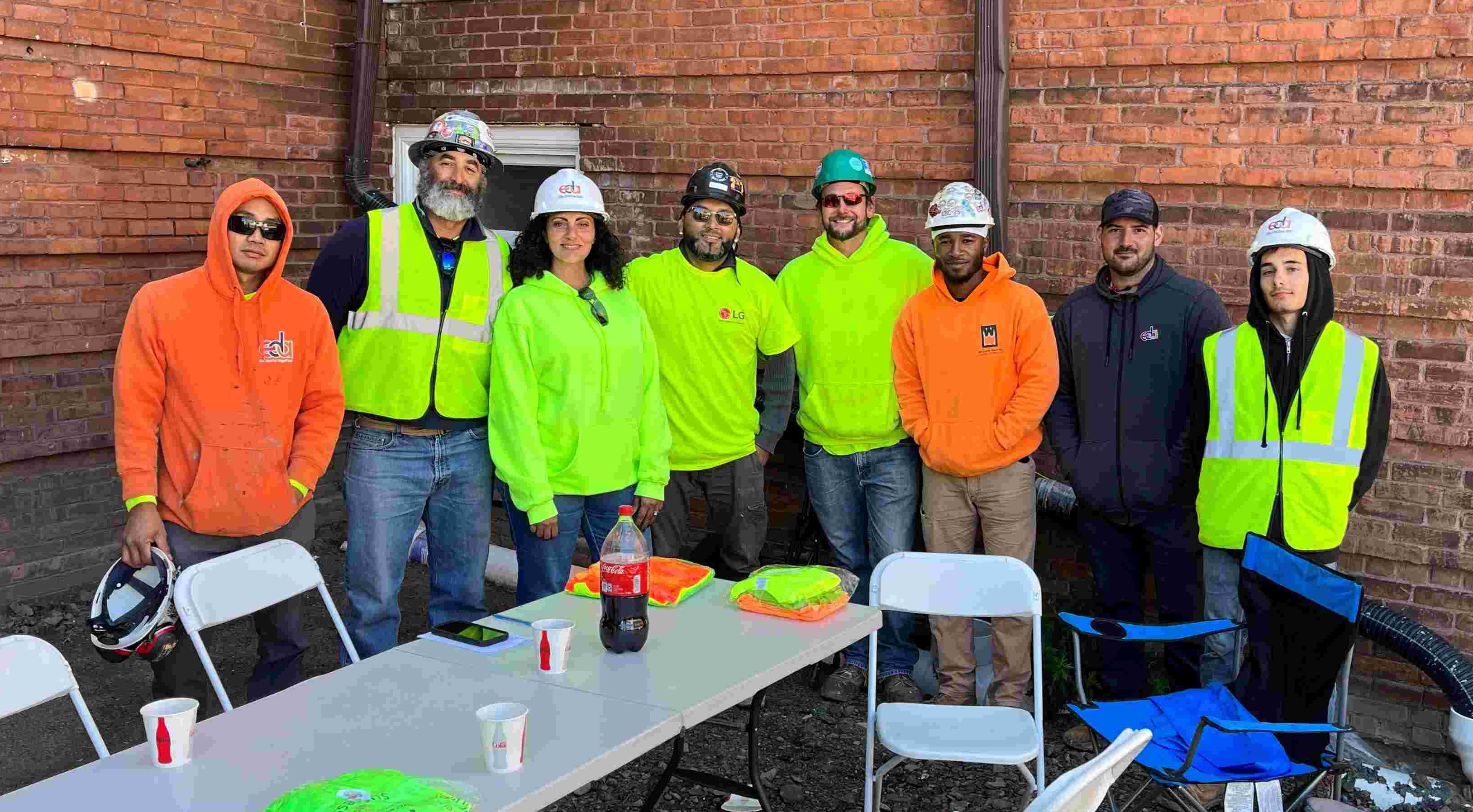 Group of EDA employees in high viz with arms around each other